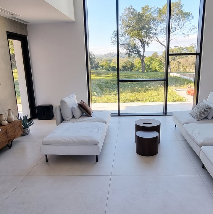 Salon contemporain encadré par un mur-rideau en aluminium noir mat ouvrant sur un jardin — projet Aluminium Tanger à Boubana